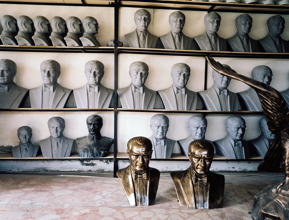 Multiple plaster and bronze busts and statues of Ataturk displayed on shelves in sculptor Necati Inci's studio.