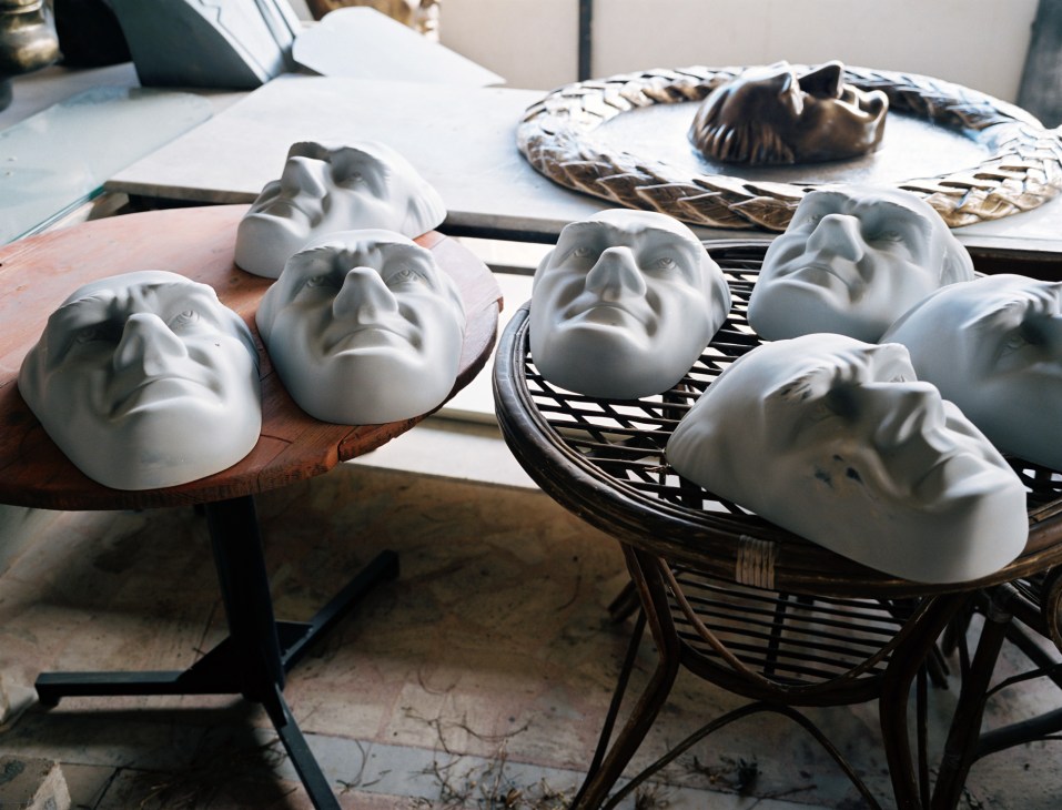 Multiple white plaster bust molds of Ataturk's head arranged on a work table in a sculptor's studio.