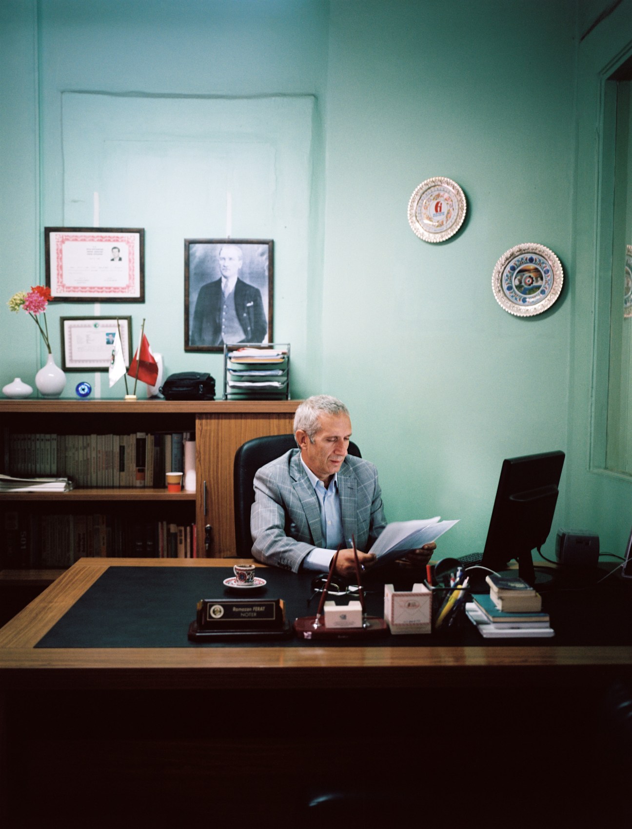 Public servant Nedim Saridag sits at his desk in a notary office with a portrait of Ataturk hanging on the wall behind him.
