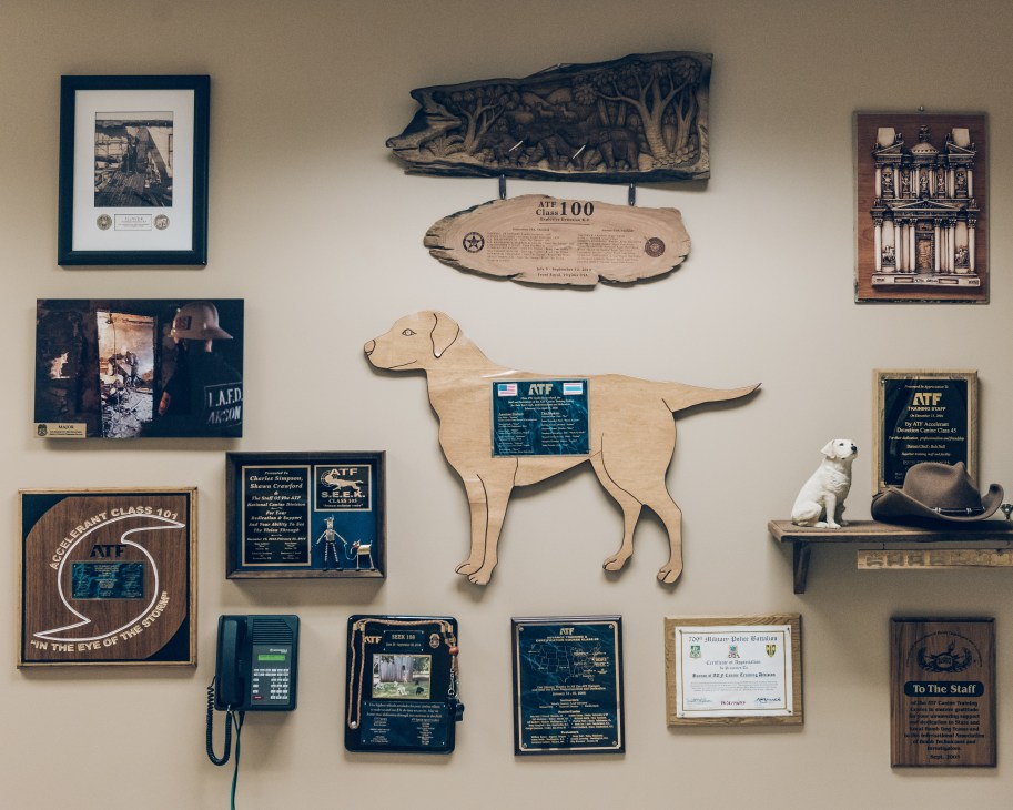 Wall display of ATF memorabilia and wooden dog-shaped plaques honoring retired canine officers.