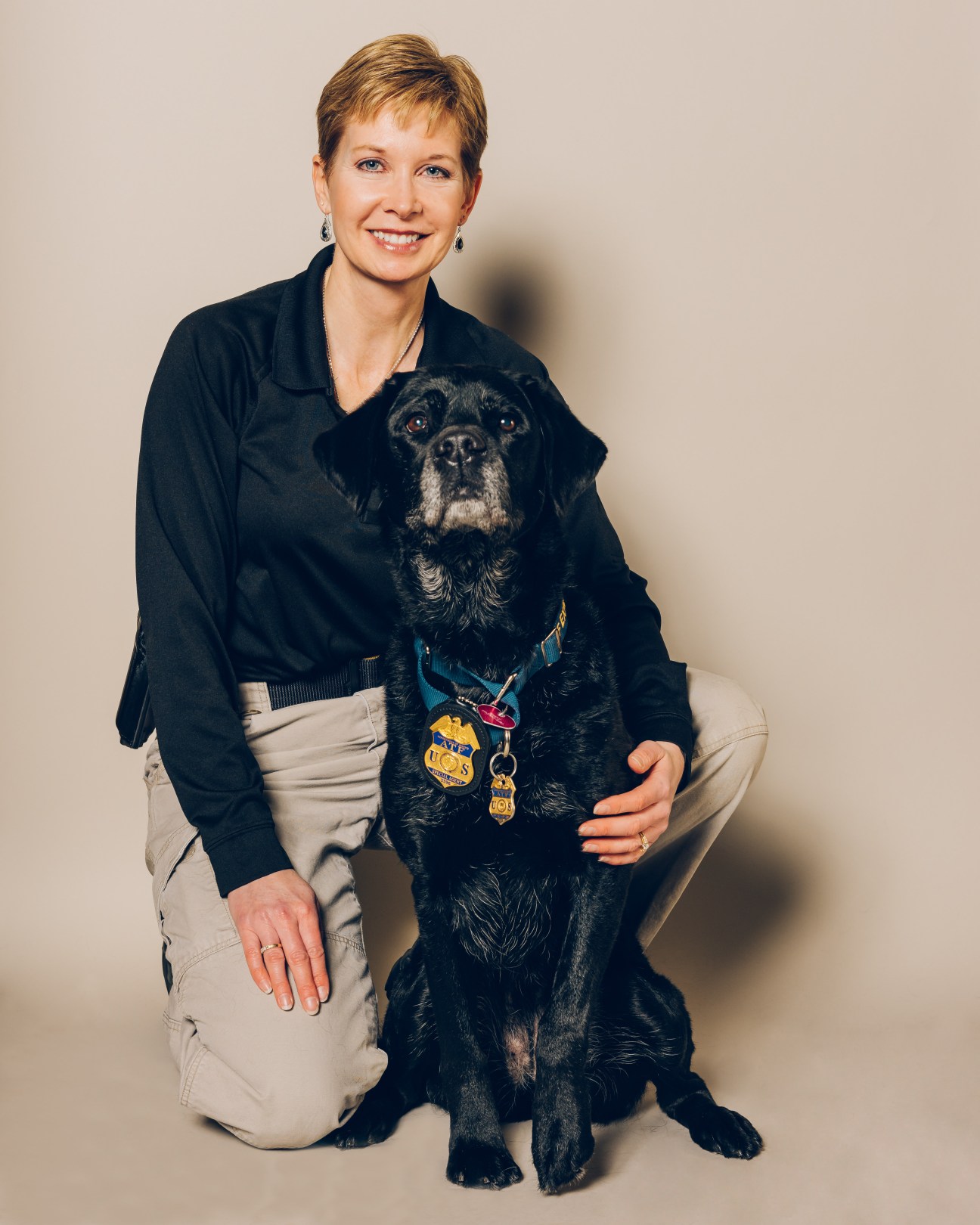 Sheila Fry with Sunny, a black labrador wearing ATF medals and badges.