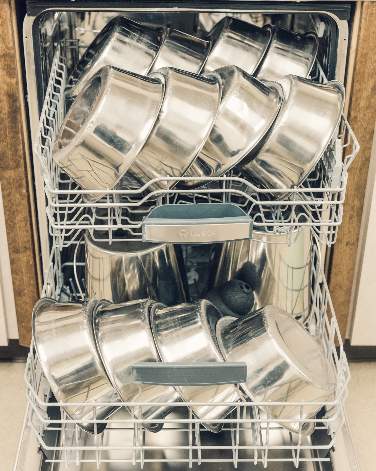 Open dishwasher filled with metal bowls and training equipment used at ATF canine center.