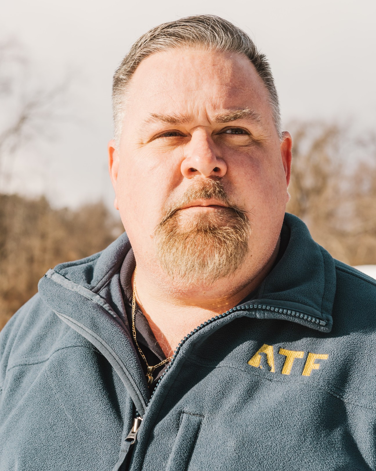 Shawn Crawford, a man with a goatee wearing an ATF fleece jacket, poses outdoors.