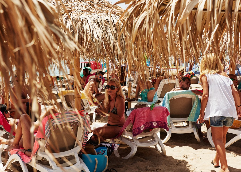 Beachgoers relax under thatched umbrellas at Varkiza resort beach in Athens.