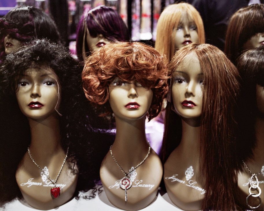 Mannequin heads displaying various wigs and hair extensions at Not Your Mama's Wig booth.