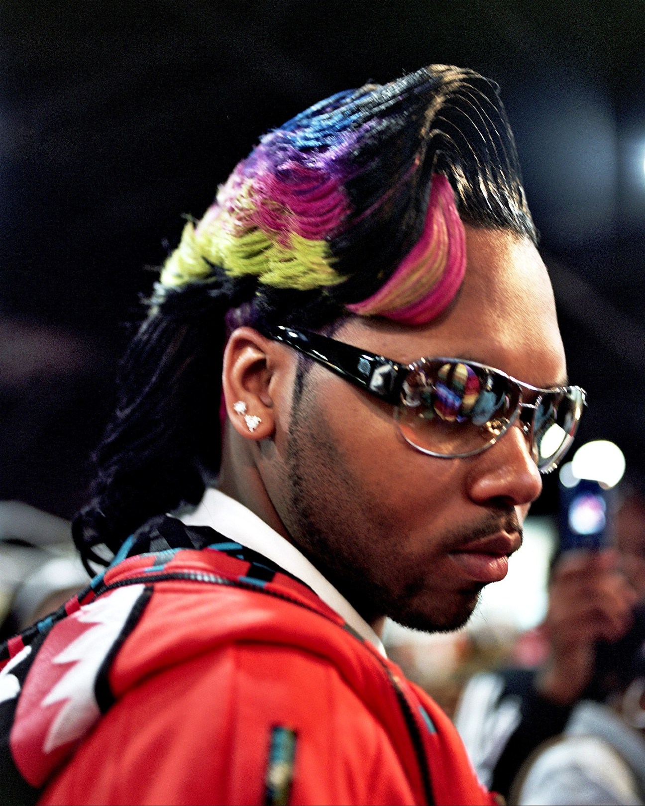 Model Antoine Wright wearing multicolored feathered hair and dark sunglasses.