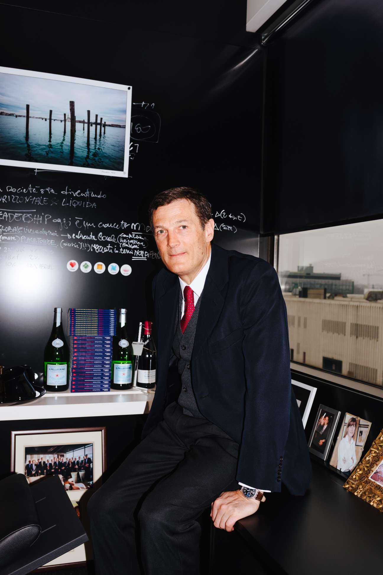 Autogrill CEO Gianmario Tondato Da Ruos sits in his office with wine bottles and design sketches visible behind him.