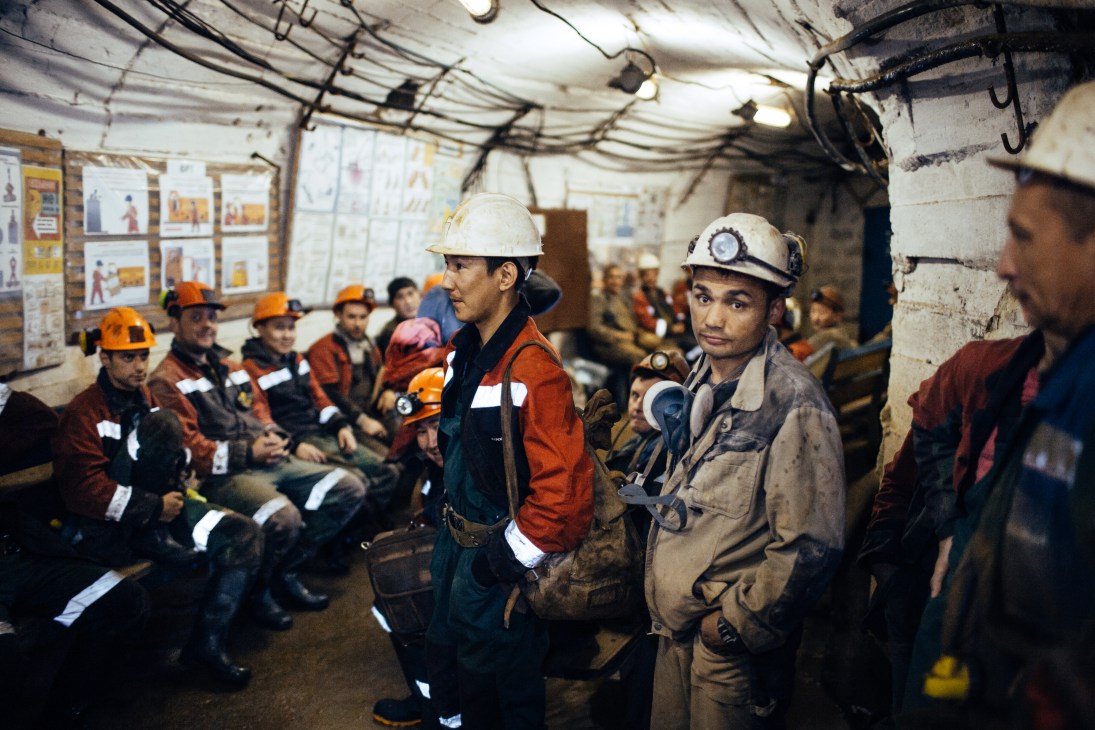 Miners in hard hats and work clothes gathered underground waiting for a lift after their shift at the International mine near Mirny, Yakutia.