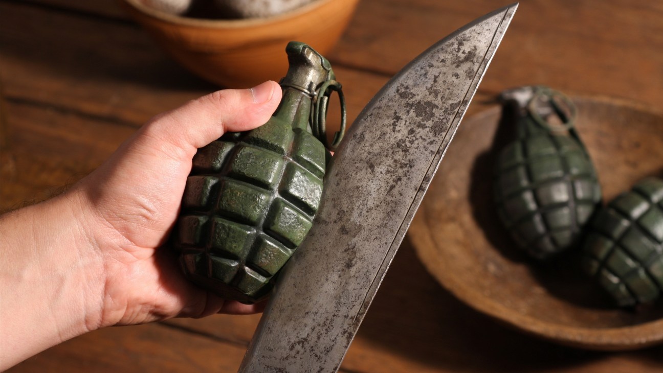 Hand holding a green grenade-shaped object next to a knife for the film Fresh Guacamole.