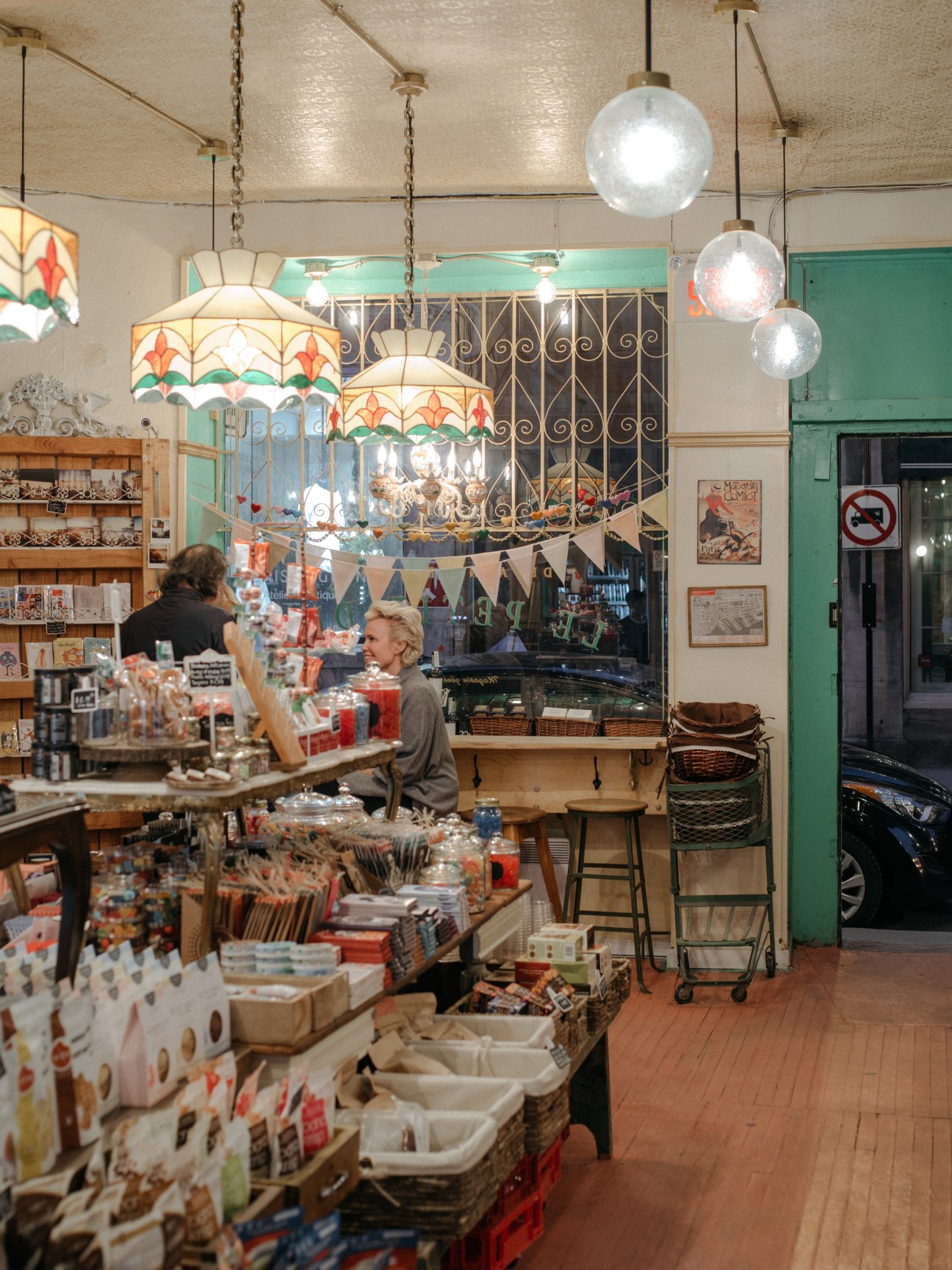 Interior of Le Petite Dep shop with vintage décor, hanging globe lights, and shelves of merchandise.