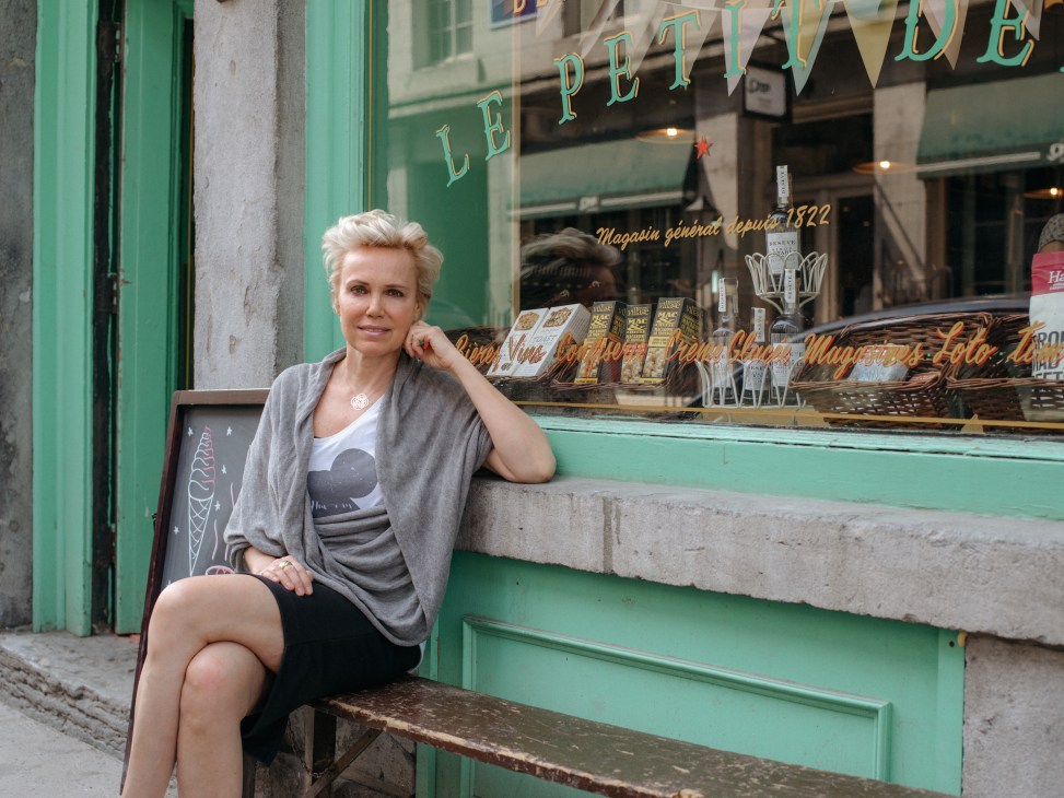 Magda Slezak sits outside her Parisian-inspired general store in Old Montréal with green storefront signage.