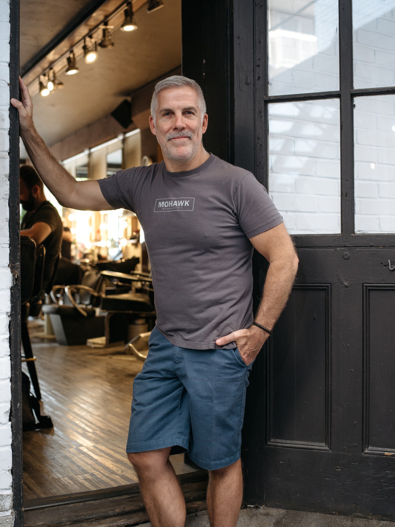 Jean-Marc Cardinal stands in the doorway of Mohawk Barbiers wearing a branded t-shirt.