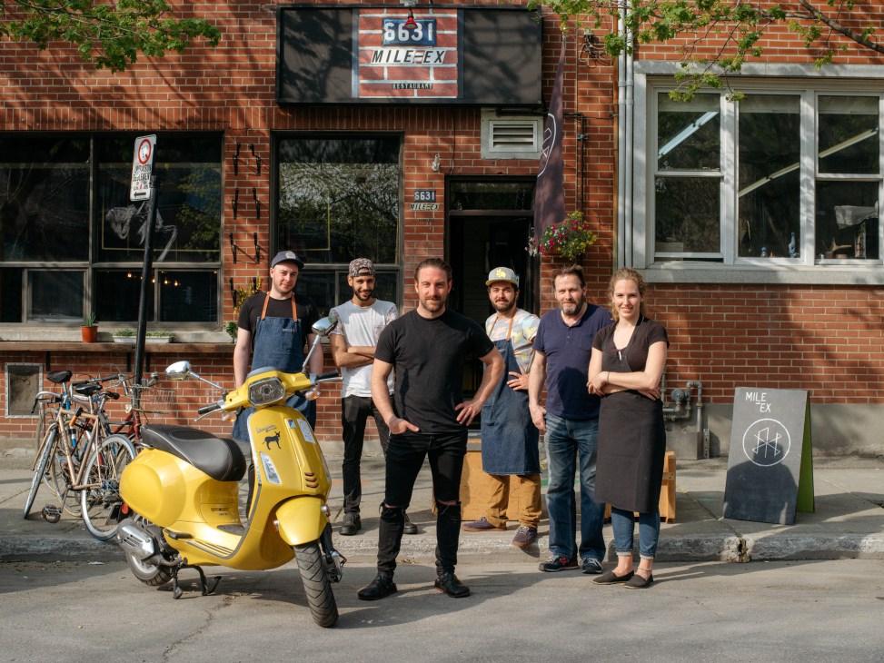 Mile-Ex restaurant team of six people standing outside brick building with yellow Vespa scooter, led by chef Gregory Paul third from left.