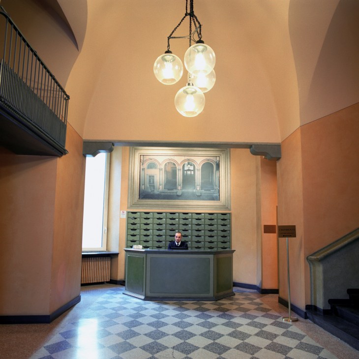 Boccia pendant lamps hanging in a lobby with peach walls, geometric floor tiles, and a reception desk.