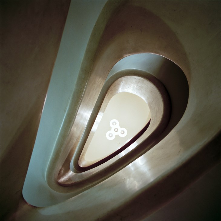 Upward view of a spiral marble staircase with curved walls at Teatro Filodrammatici.
