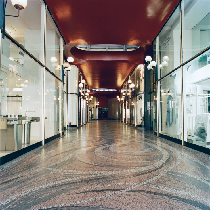 Galleria Strasburgo shopping arcade with globe pendant lamps and swirling mosaic floor.