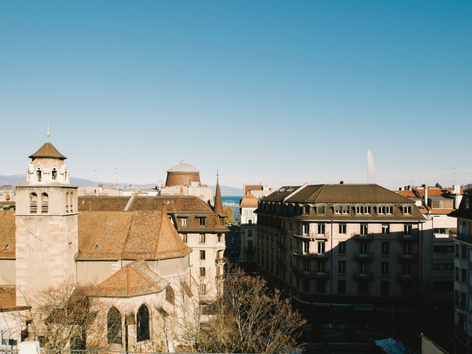 Geneva's old town with historic church, traditional architecture and Lake Geneva visible in the distance.