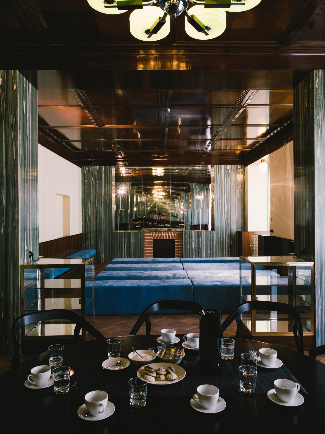 Restored modern interior with mahogany-tiled ceiling, mirrored walls, and dining furniture at Bendova 10.