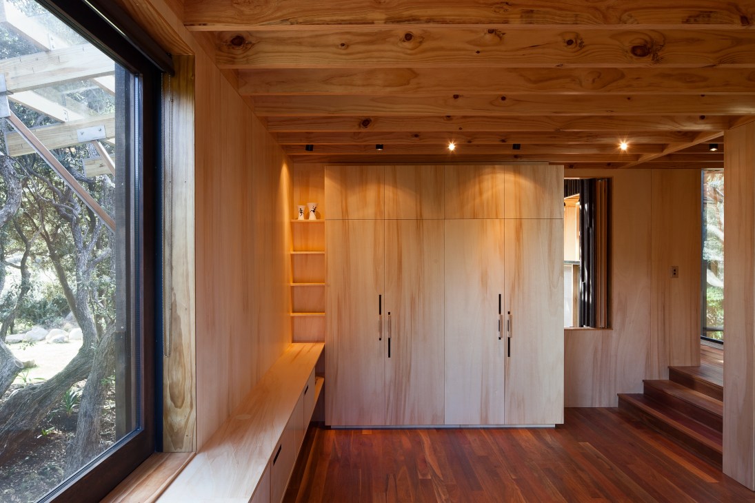 Wooden bedroom entrance with built-in cupboards and shelving in Butler Beach House by Herbst Architects.