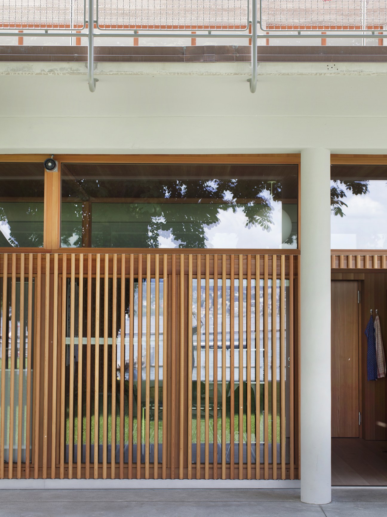 Larch wood slat screening with large windows and white concrete column at Strandbad Wollishofen.