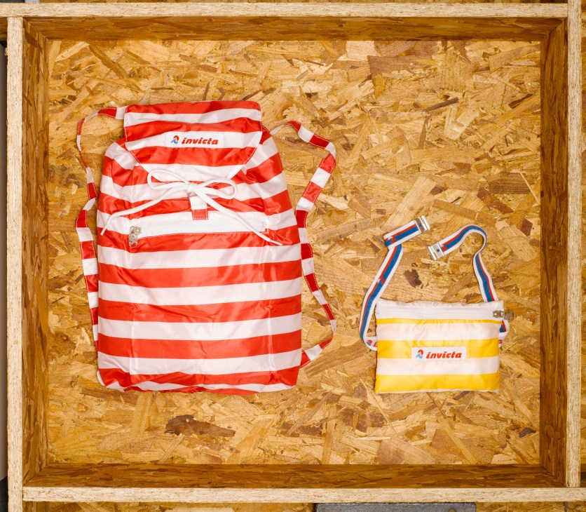 Invicta striped packaway bags in red and white with yellow accents displayed in a cork-lined box.