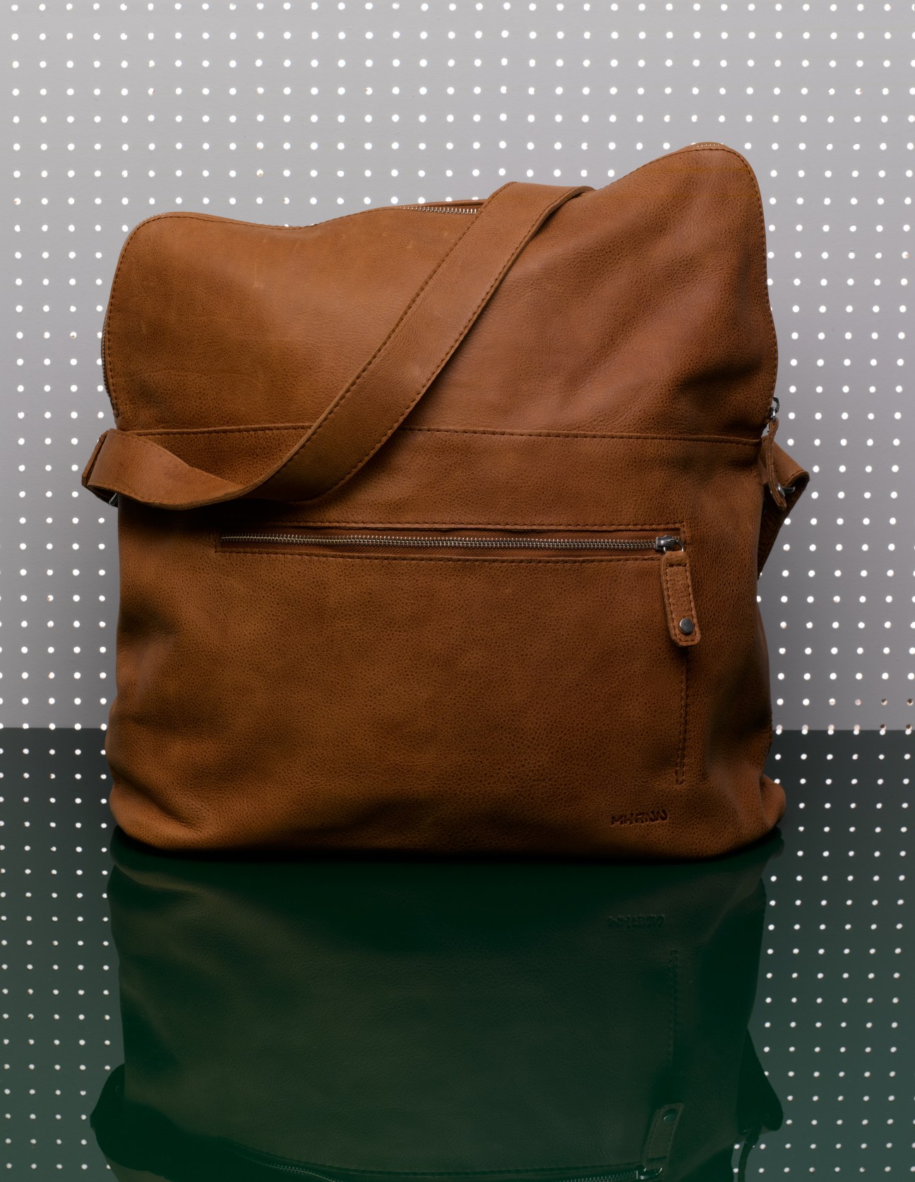 Brown leather Lumi Supermarket travel bag with shoulder strap and front zipper pocket.