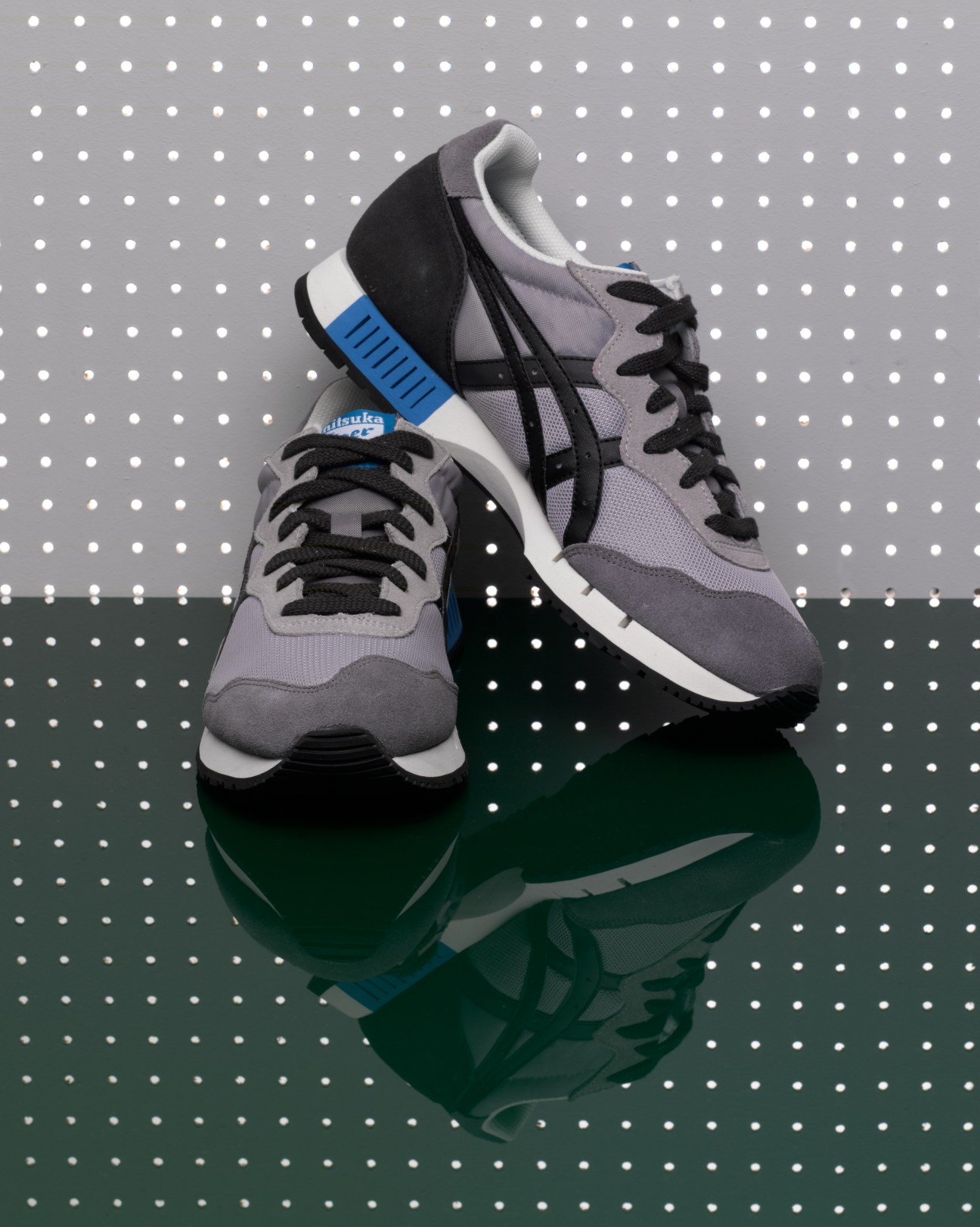 Onitsuka Tiger Asics XCaliber running shoes in gray, black and blue on polka dot background.