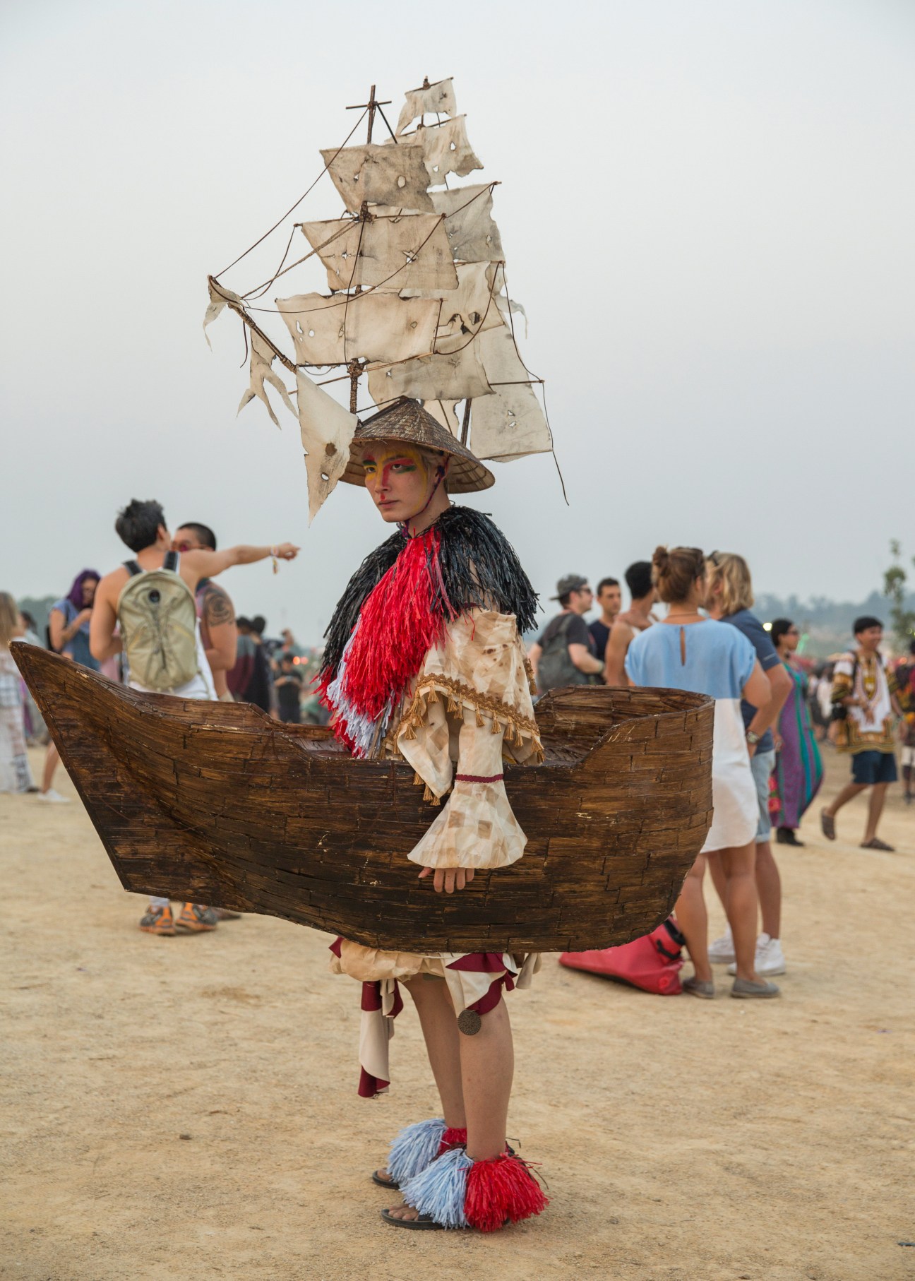 Festival attendee in elaborate ship-themed costume with sail headdress and wooden boat frame at Wonderfruit festival.