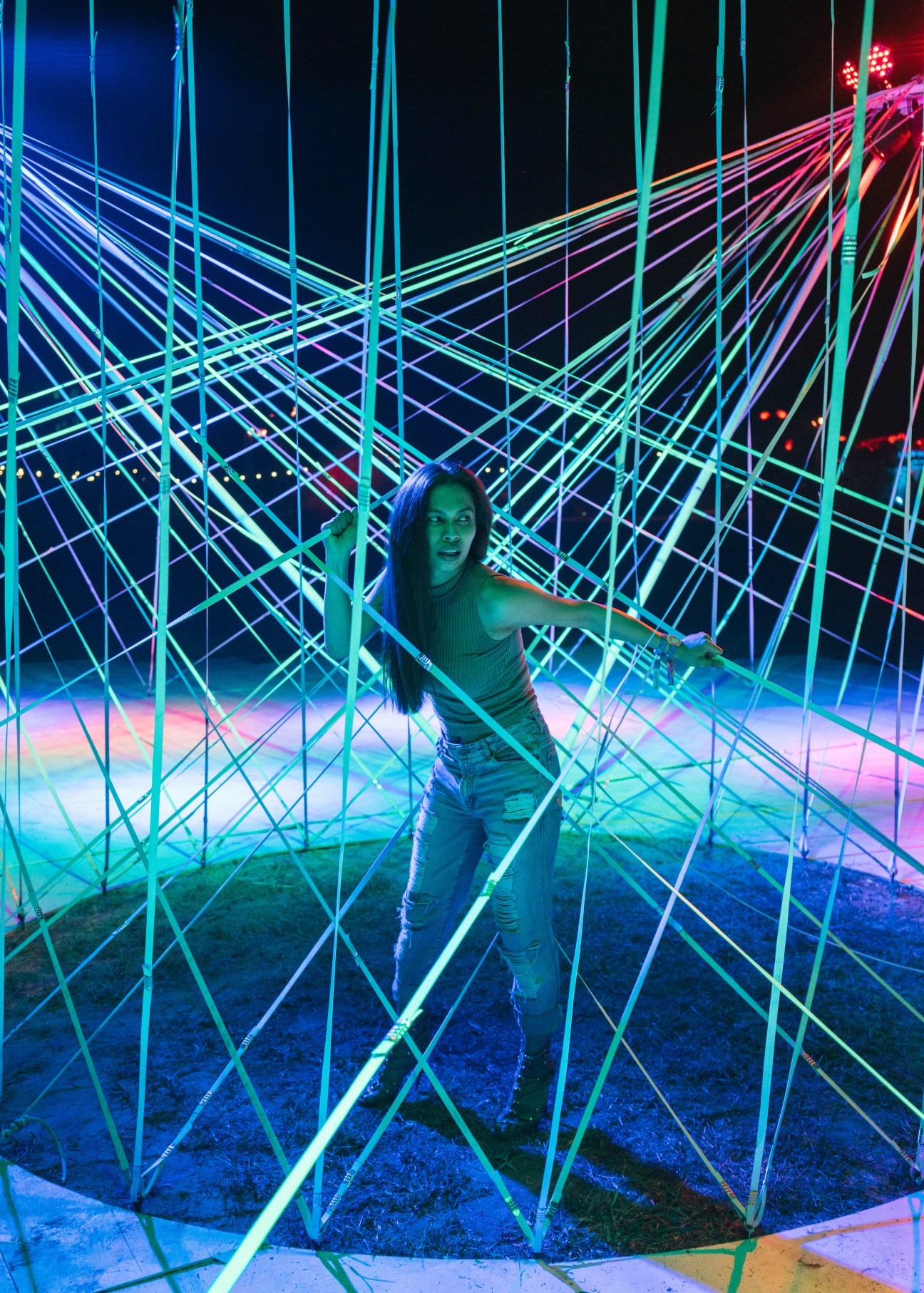 Woman posing inside a geometric neon light installation at Wonderfruit festival in Thailand.