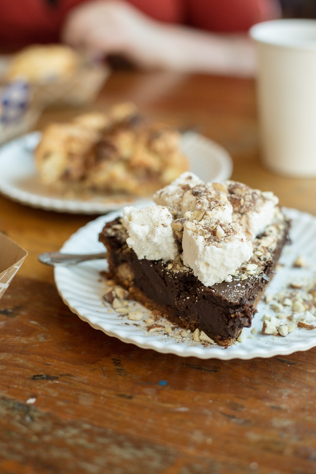 Slice of chocolate pie with whipped cream topping on a white plate.