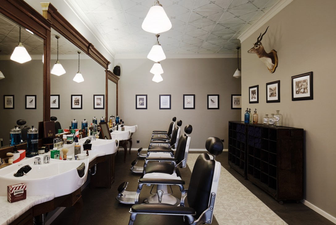 Interior of Barber House Munich with barber chairs, mirrors, pendant lights and framed photographs on walls.