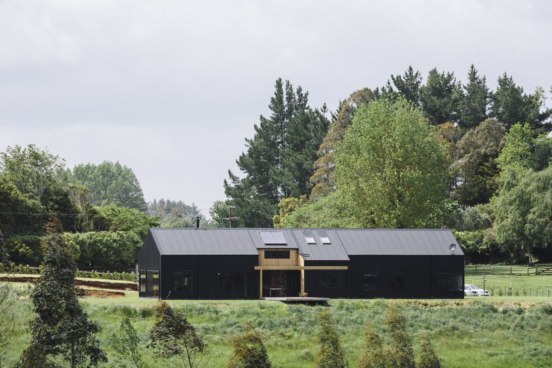 Modern barn-style house with corrugated steel roof and timber accents set in New Zealand countryside