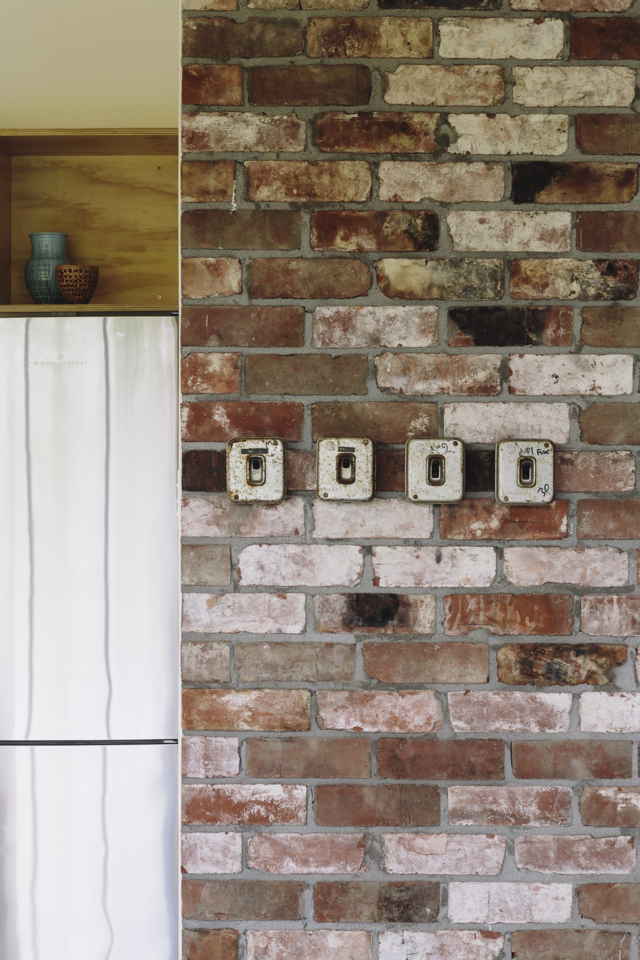 Reclaimed vintage switches mounted on a brick wall with salvaged bricks from the Christchurch earthquake.