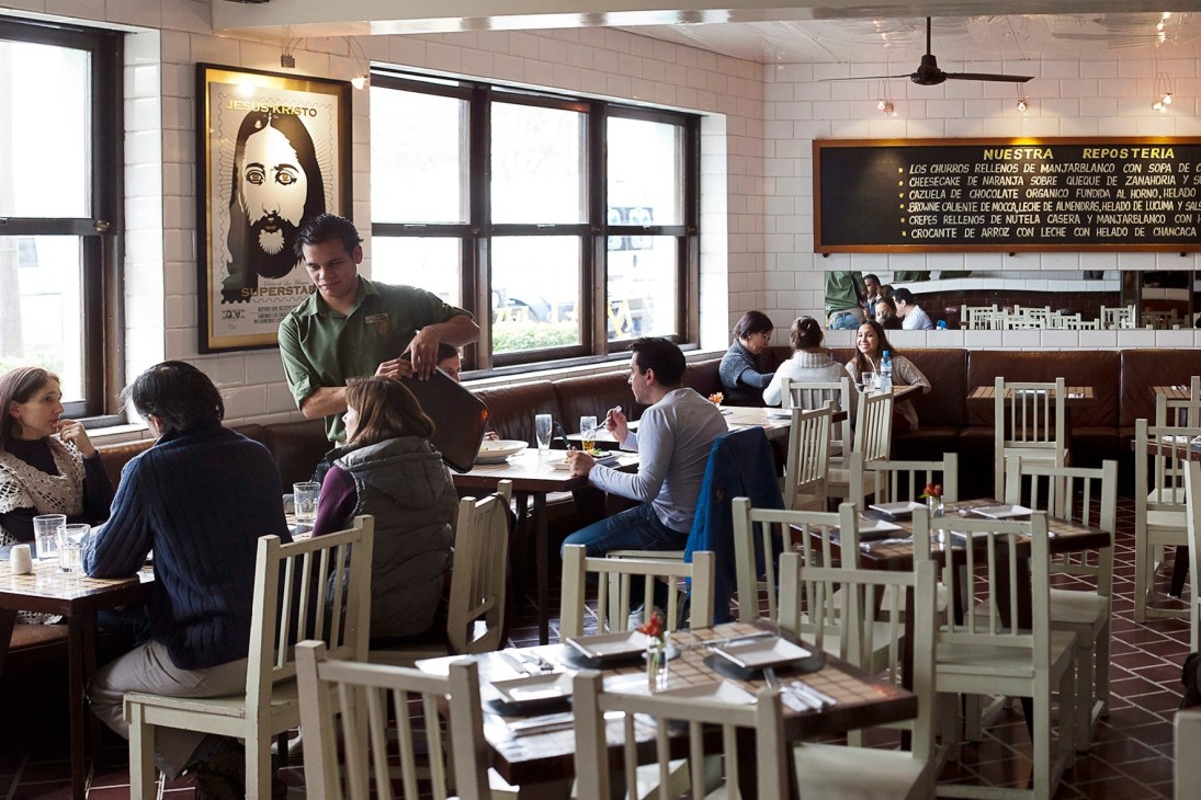 Diners seated at tables in La 73 restaurant with cream-colored chairs and bright windows.