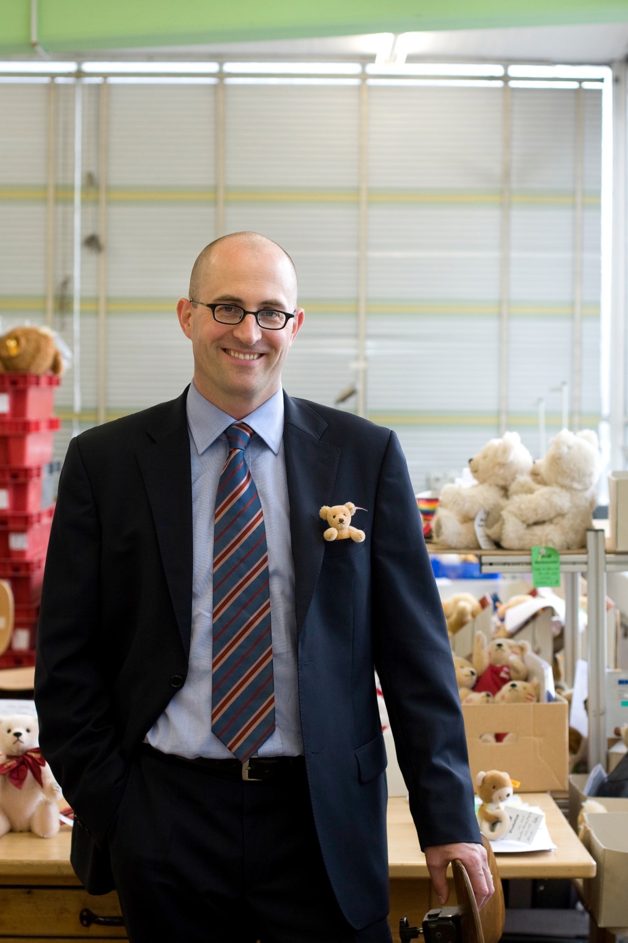 Martin Frechen, managing director of Steiff, smiles at the camera in the toy factory surrounded by teddy bears.