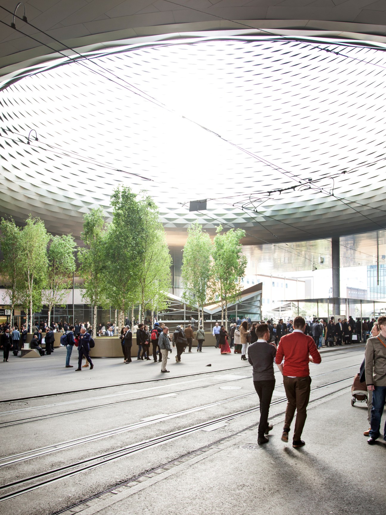 Visitors and attendees walk beneath the modern architectural roof of the Baselworld exhibition centre.