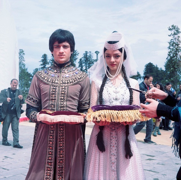 Young man and woman in traditional Georgian costumes with embroidered details at Expo Batumi.