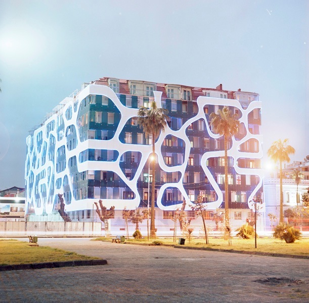 Modern white residential building with organic curved window shapes and Georgian lettering design in Batumi.
