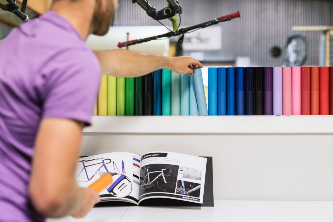 Baum Cycles craftsperson selecting from a range of paint color samples displayed on cards.