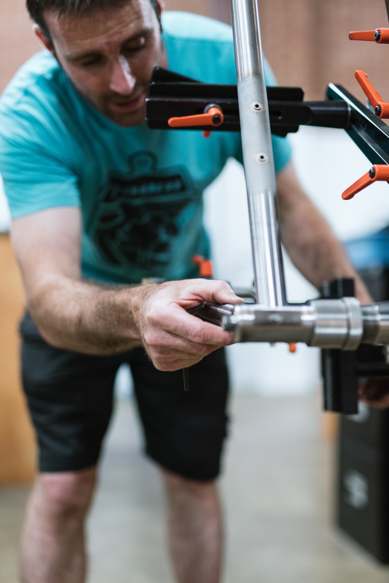 Baum Cycles craftsperson aligning frame components on a bicycle during handcrafted assembly.