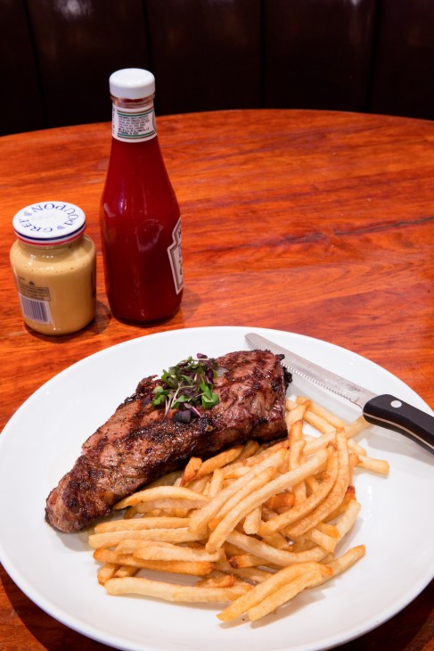 New York shell steak with chips, Dijon mustard and ketchup on a white plate at the Knickerbocker restaurant