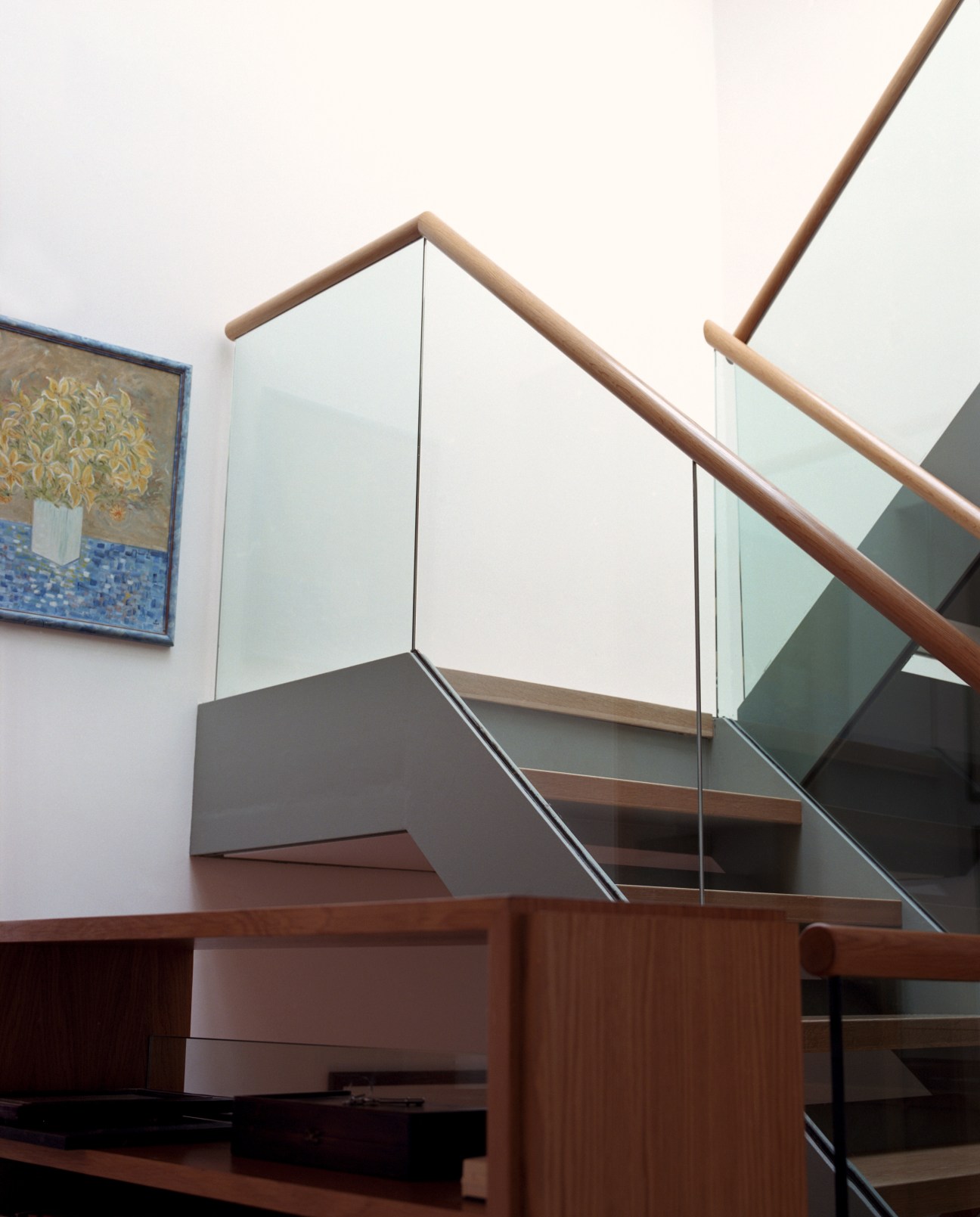 Interior stairwell with wooden railings and glass panels allowing natural light through