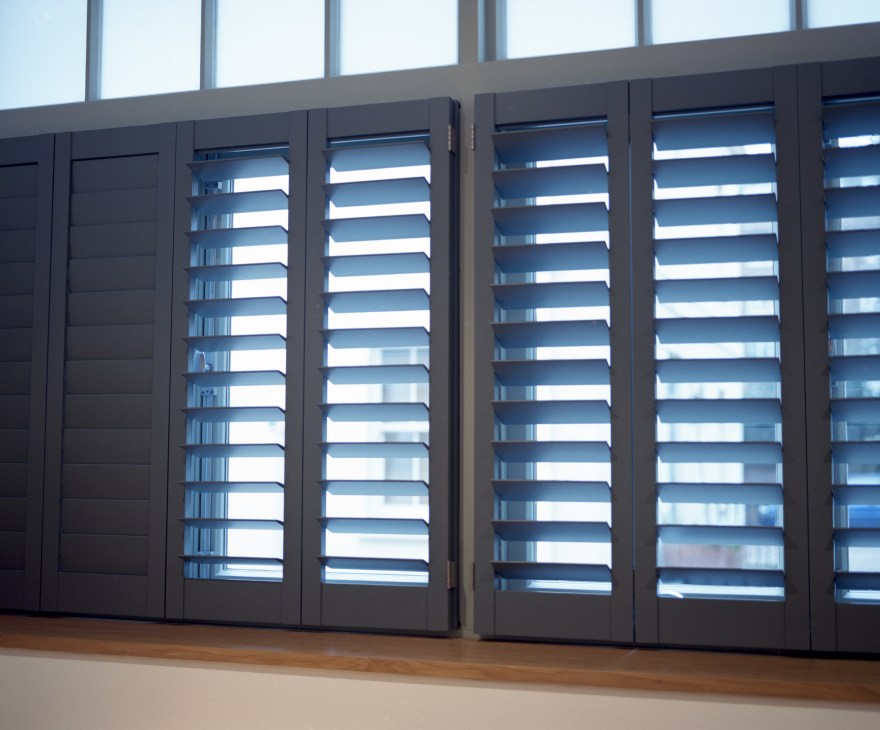 Dark shutters with horizontal louvres provide security and insulation on a modern building facade.
