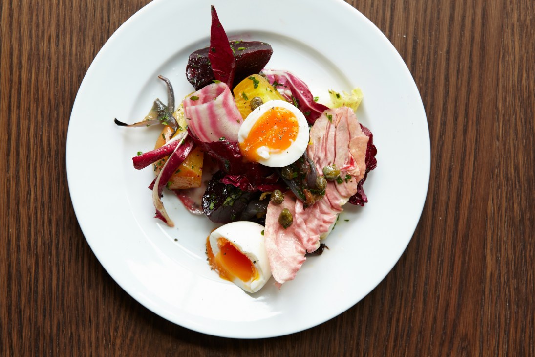 Plated dish at Beagle restaurant featuring beetroot, bitter leaves, sliced meat, soft-boiled eggs and capers on white plate.