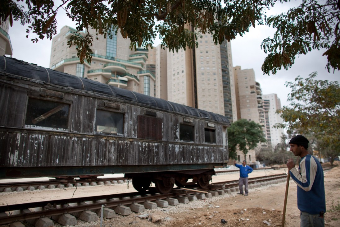 Abandoned Ottoman railway station with deteriorated wooden structure against modern high-rise buildings in Be'er-Sheva.