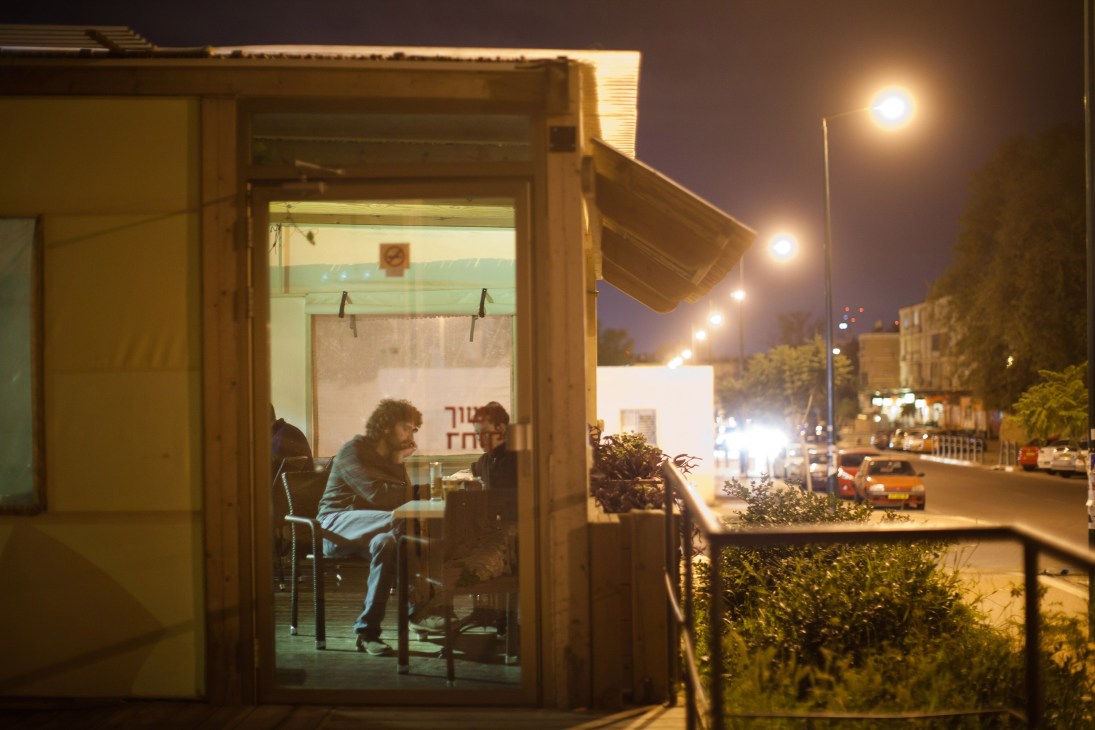 People seated inside Ringelblum café at night with street lights visible through windows.