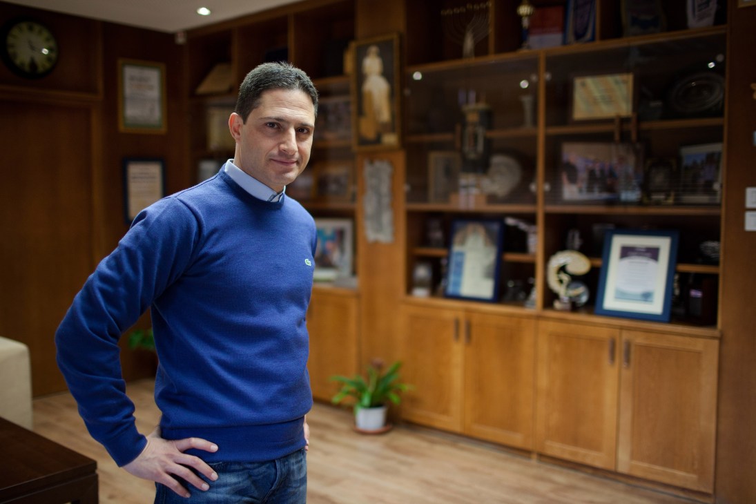 Ruvik Danilovich, mayor of Be'er-Sheva, stands in his office with wooden display cabinets behind him.