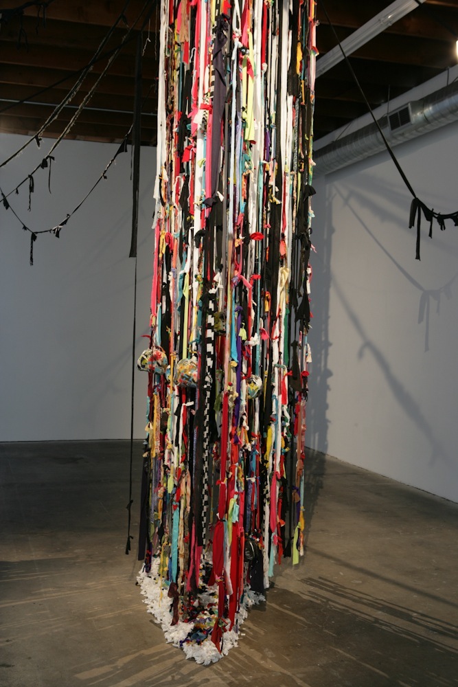 John Outterbridge's 'The Rag Factory' (2011), a suspended sculptural installation of multi-colored fabric strips hanging from the ceiling in a gallery space.