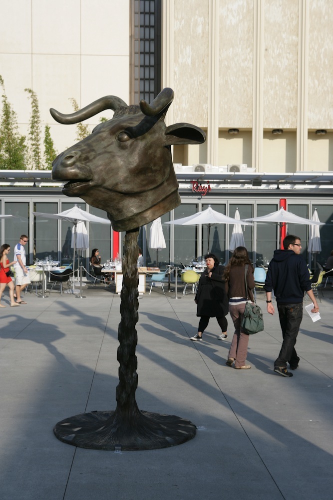 Ai Weiwei's bronze bull head sculpture installed in LACMA's North Piazza with visitors nearby.