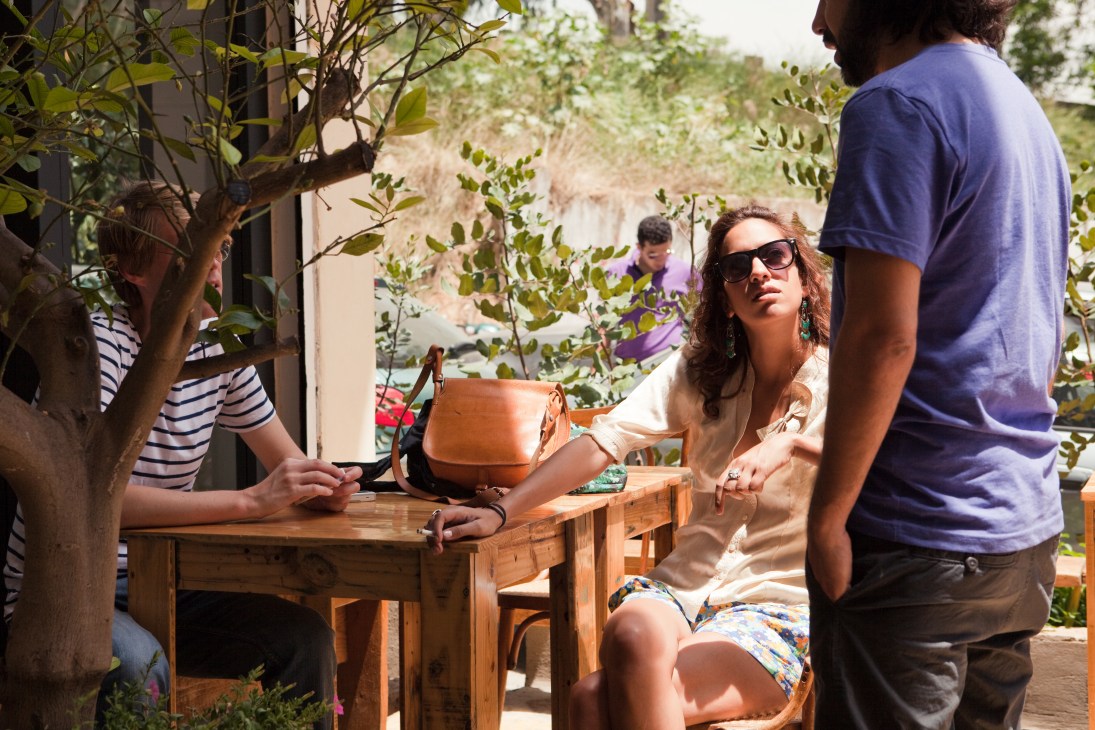 People socializing at Tawlet buffet restaurant in Mar Mikhael, Beirut, with greenery and wooden furniture.